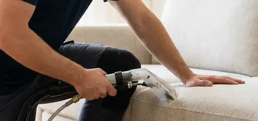 Professional upholstery cleaner deep-cleaning a fabric sofa with a handheld extraction tool, Clearwater, FL.